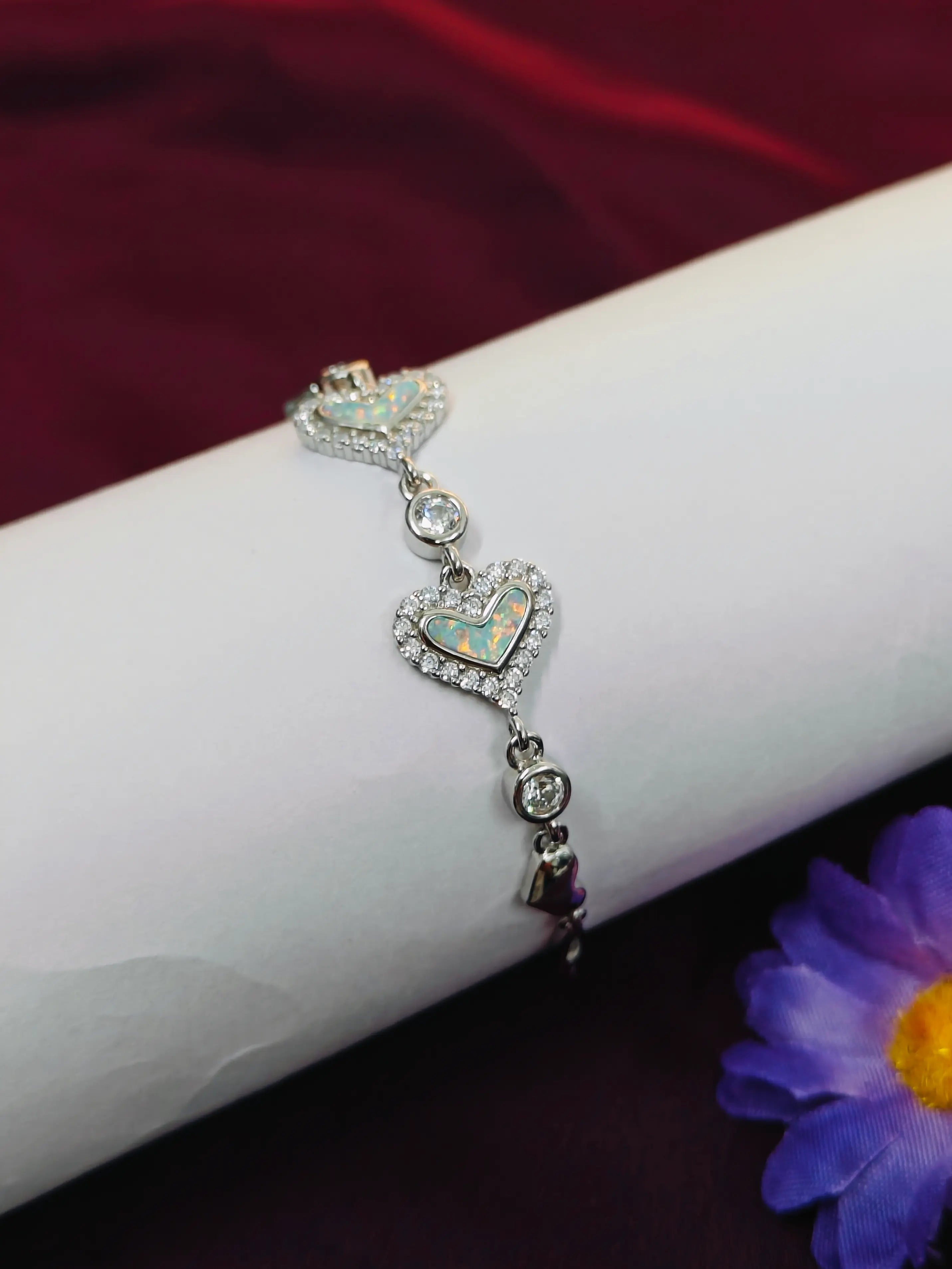 Silver bracelet with heart-shaped charms on a wrist against a dark background